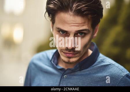Young bearded guy with modern hairstyle looking at camera. Stock Photo