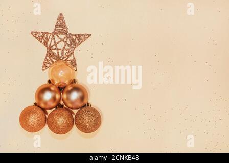 Christmas tree made of golden baubles and star on beige background, copyspace for text. Christmas, New Year concept Stock Photo