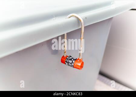 The plastic locker lock placed near the gray and red smoke alarm is also a combination of gray and red. Stock Photo