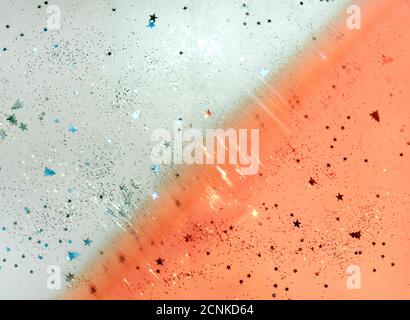 Scattered glitter on blue and orange color background, Christmas, New year decorations. Stock Photo