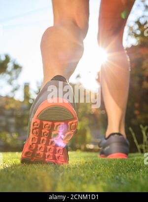 Female athlete runner feet running on the grass, closeup on shoes. Woman outdoor fitness jogging and training concept, healthy lifestyle Stock Photo