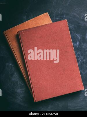 Blank books on black board background. Old vintage cloth hard cover book, cover template, top view, vertical Stock Photo