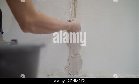 Plastering the wall. Hands Plasterer at work. Application of the plaster on the wall. textured plaster Stock Photo