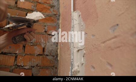 Decorative plaster coating. Man does ragged texture on the wall using a spatula. plaster application on the wall Stock Photo