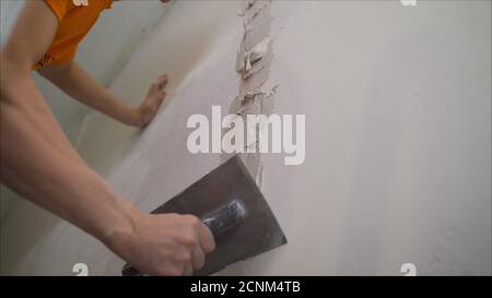 Worker using the trowel for plastering the concrete wall at the construction site. Making the smoothness and flat the surface of cement wall by wooden Stock Photo