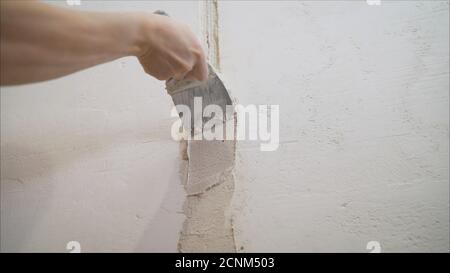 Worker spreads mortar on the wall. Wall repair in a new apartment. Hand of worker with plaster and trowel to gypsum board Stock Photo