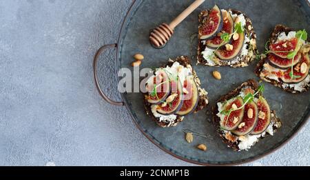 Sandwiches with fresh figs, cream cheese, nuts and honey on tray top view Stock Photo