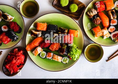 Overhead view of a nigiri and maki roll sushi selection with wasabi, pickled ginger and green tea Stock Photo