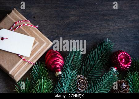 Stack of Christmas gifts next to pinecones, fir branches and Christmas ornaments on a wooden table Stock Photo