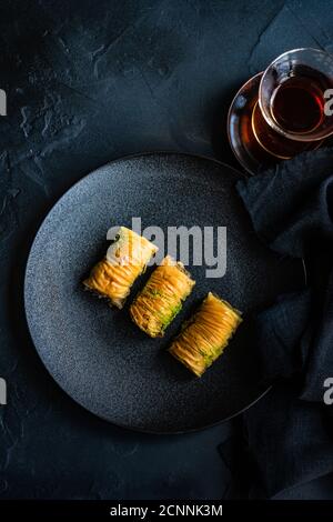 Three baklava desserts on a plate with black tea Stock Photo
