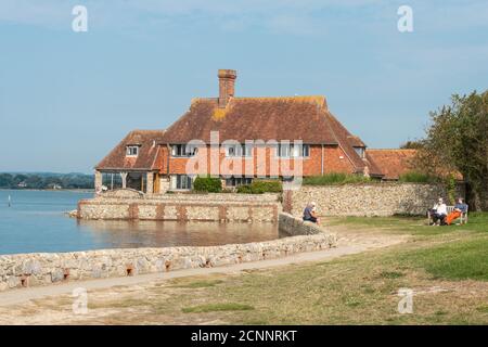 Visitors sitting relaxing on the lawn overlooking Bosham Quay, a picturesque seaside village in West Sussex, UK Stock Photo