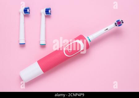Electric toothbrush and round brush heads or nozzles on a pink paper background. Teeth cleaning, oral hygiene and healthy care concept. Top view Stock Photo