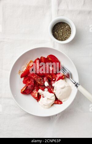 Roasted tomatoes with sour cream in a plate. Stock Photo