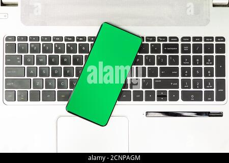 Green screen smartphone on the laptop keyboard top view Stock Photo