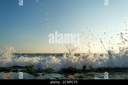 Sea waves breaking on a stony shore, forming sprays and splashes Stock Photo