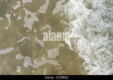 Aerial top view of white waves and water tide coming in at the beach. Stock Photo