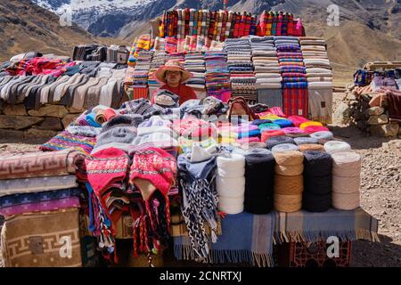 A roadside market in the Altiplano high Andes, Peru, selling textiles and fabrics, clothes and tourist souvenirs Stock Photo