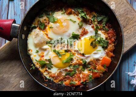 Top view of Shakshuka, a middle eastern delicacy in a black pan on a background