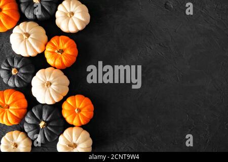 Autumn pumpkin side border in Halloween colors orange, black and white against a black stone background. Copy space. Stock Photo