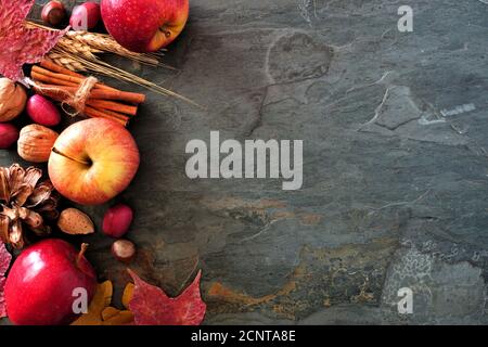 Autumn side border of apples, fall foods and decor on a dark stone background with copy space Stock Photo