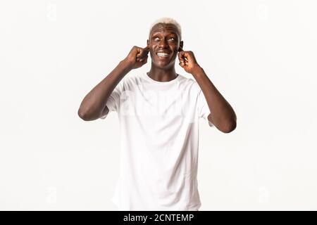 Portrait of annoyed african-american guy feeling discomfort from loud neighbours, shut ears bothered, standing white background Stock Photo
