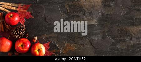 Autumn corner border banner of apples, leaves, and fall decor. Top view on a dark stone background with copy space. Stock Photo
