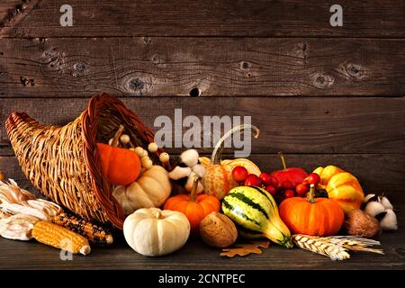 Thanksgiving cornucopia filled with autumn pumpkins and vegetables against a rustic dark wood background Stock Photo