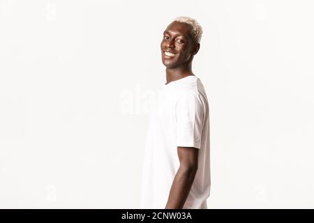 Portrait of happy handsome african-american blond guy turning face at camera, smiling cheerful and standing white background Stock Photo