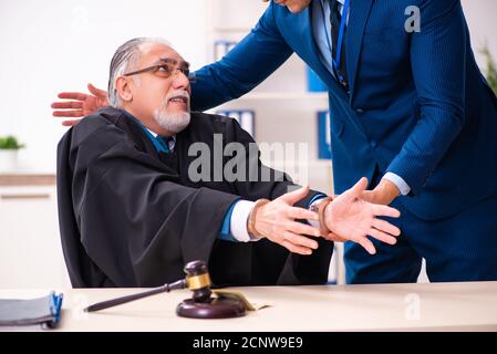 Police inspector arresting judge in court Stock Photo