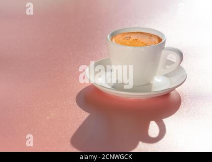White cup of coffee on light pink background in natural soft morning sunlight. Pink mood. Copy space Stock Photo