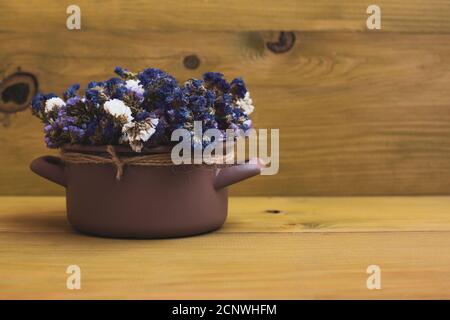 Beautiful dried flowers in cooking pan on wooden background. Stock Photo