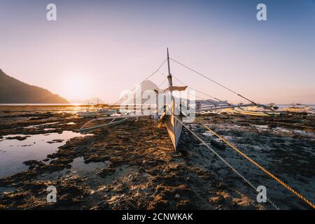 El Nido, Banca boat in low tide with beautiful sunset in background. Palawan island, Philippines. Stock Photo