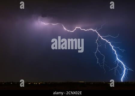 Stormy weather with a dramatic thunderstorm lightning strike in the night sky over Queen Creek, Arizona Stock Photo