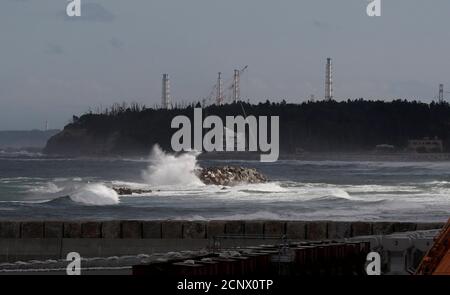Wave is seen in front of cranes and chimneys of Tokyo Electric Power Co's (TEPCO) tsunami-crippled Fukushima Daiichi nuclear power plant at an area devastated by the March 11, 2011 earthquake and tsunami in Namie town, Fukushima prefecture, Japan May 19, 2018. Picture taken May 19, 2018.  REUTERS/Toru Hanai