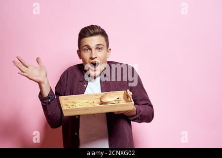 Man with wooden pallet fast food diet food lifestyle pink background Stock Photo