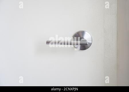 Close-up of a stainless steel door handle on indoor white door Stock Photo