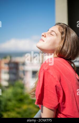 Young Girl Closing Her Eyes When the Sun Touches Her Face. Home Concept Stock Photo