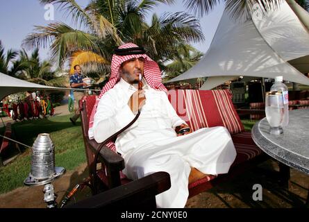A Saudi man smokes a water pipe as he sits on a beach in Jeddah city in Saudi Arabia April 14, 2005. REUTERS/Ahmed Jadallah  AJ/VP