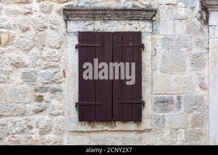 Closed brown wooden window shutters on an beautiful old stone seaside house. Stock Photo