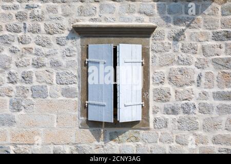 Window with open white shutters on an old stone seaside house. Stock Photo