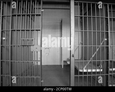 Black and white view inside empty jail cell block in an closed rundown government owned facility. Stock Photo
