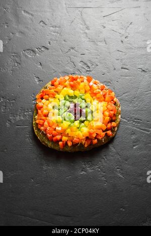 Rainbow veggie bell peppers pizza on black stone background with free text space. Vegetarian vegan or healthy food concept. Gluten free diet dish. Stock Photo