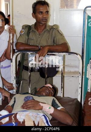 A Sri Lankan policeman stands guard at the hospital bedside of a conductor in Kurunegala, central Sri Lanka.  A Sri Lankan policeman stands guard at the hospital bedside of the conductor of the ill-fated bus which collided with an express train in Kurunegala, central Sri Lanka April 27, 2005. More than 50 bus passengers were feared killed and about 40 injured when a train rammed into the crowded vehicle at a level-crossing in Sri Lanka on Wednesday, crushing it and setting it on fire, officials said. REUTERS/Anuruddha Lokuhapuarachchi