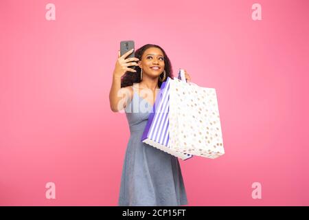 pretty black lady taking a selfie with her phone while holding some shopping bags Stock Photo