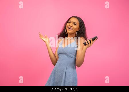 excited black lady holding her phone shrugs her hand Stock Photo