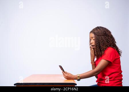 side view of excited young black lady using her phone looking surprised Stock Photo