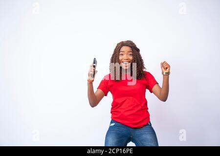 young black lady holding her phone feeling excited and celebrating Stock Photo