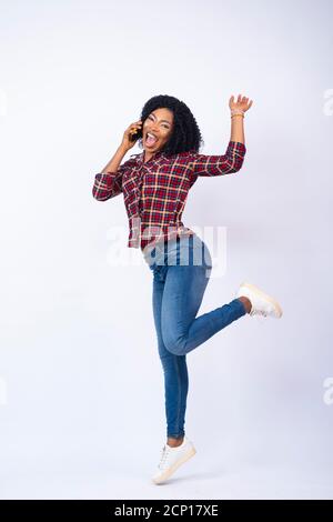 happy pretty young black woman making a phone call jumps in excitement Stock Photo
