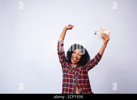 pretty young african lady holding a wad of cash celebrating Stock Photo