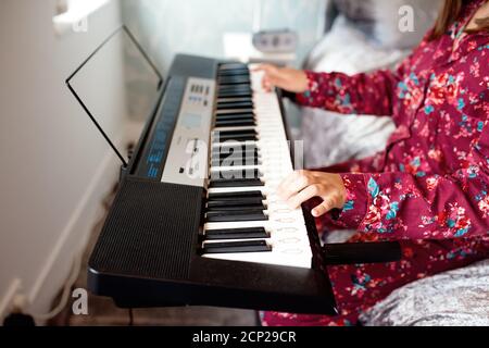 Girl in pajamas playing piano in a room Stock Photo